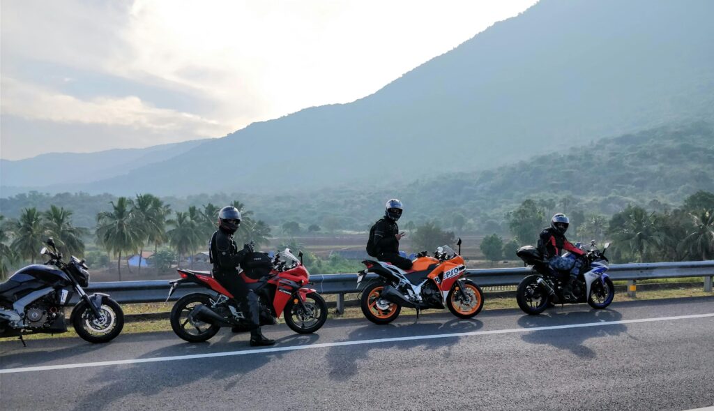 Three motorcyclists on a scenic mountain road with lush greenery in the background, enjoying a ride.